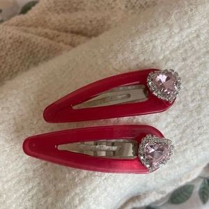 Set di fermagli a goccia con cuore di cristallo rosa su sfondo in maglia crema