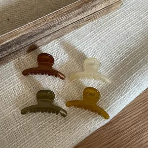 Set of four minimalist translucent resin mini hair claws in brown, cream, and mustard yellow