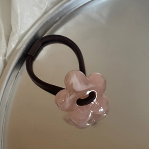 Macro shot of pink translucent floral charm on a high-elasticity hair tie band