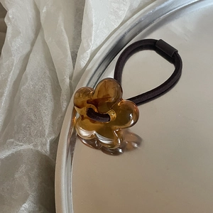 Close-up of amber flower hair tie with purple elastic band on a silver tray