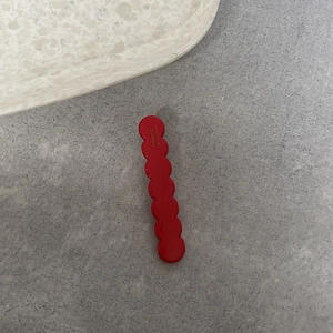 Dettaglio del fermaglio ondulato rosso con incisione France Handmade su pietra