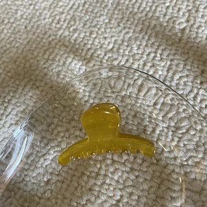 Close-up of translucent amber mini hair claw clip on a glass tray with warm lighting