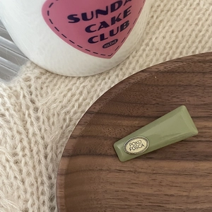 Minimalist green acrylic hair clip with gold metal plate on a wooden tray decor