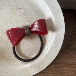 Élastique à cheveux élégant avec nœud en acétate rouge sur une assiette en céramique