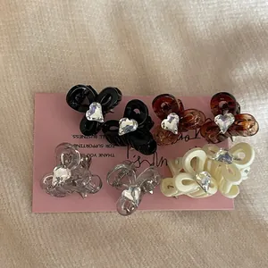 Macro shot of mini bow hair clips with heart rhinestone in black, amber, and cream colors