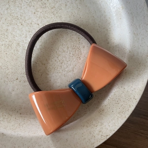 Chouchou avec nœud en acétate contrasté et élastique tressé marron sur assiette