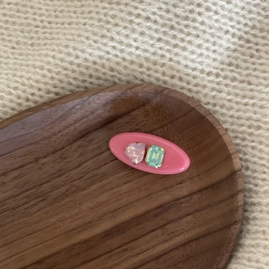Close-up of a pink oval hair clip featuring heart-shaped pink and mint green rhinestones