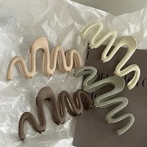 Matte wave-shaped large hair claw clips in beige, cream, coffee, and sage green
