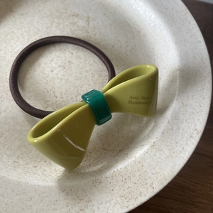 Élastique à cheveux nœud en acétate vert moutarde élégant sur une assiette
