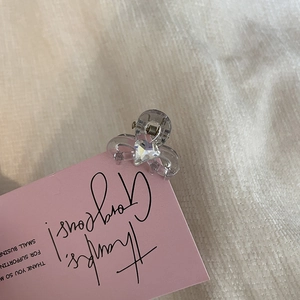 Mini transparent resin hair claw clip with a sparkling heart rhinestone on a display card