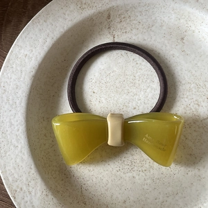 Détail d'un élastique à cheveux nœud en résine verte sur une assiette décorative