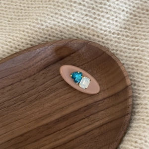 Detail view of oval hair clip with blue heart gem and white crystal on wood background