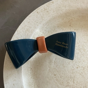 Detailansicht der marineblauen und orangefarbenen Haarklammer auf Keramiktablett
