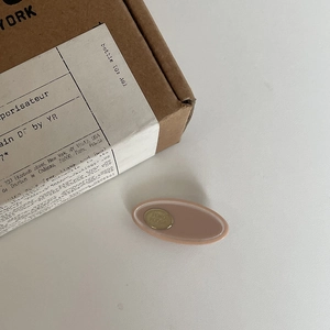 Minimalistische ovale Acetat-Haarklammer in Altrosa mit goldenem POKO POKO Metall-Logo