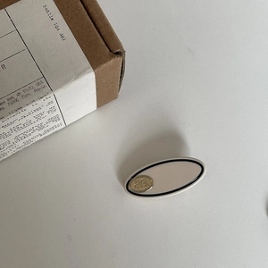 Minimalistische cremefarbene Haarklammer aus Acetat mit Goldrelief und schwarzem Rand