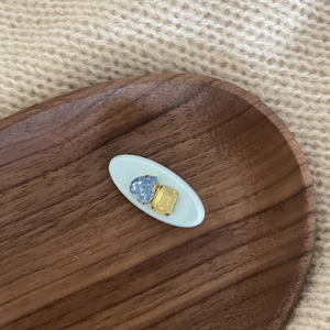 Detail view of oval hair clip with blue heart and yellow gemstone on wooden tray