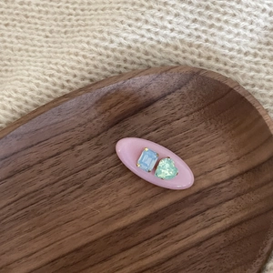 Detailed view of pink oval hair clip with blue rectangle and green heart gemstones