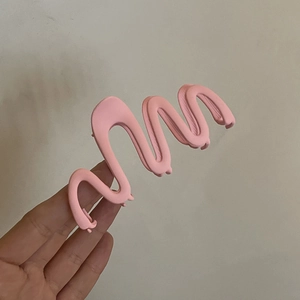 Detail of a matte pink wavy hair claw clip showing its smooth frosted texture and design