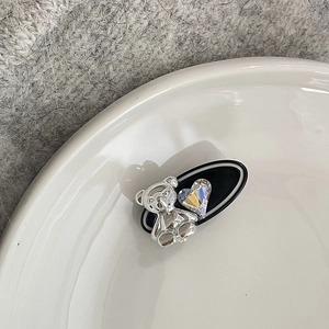 Cute bear hair clip with colorful heart crystal and black oval base on a white tray