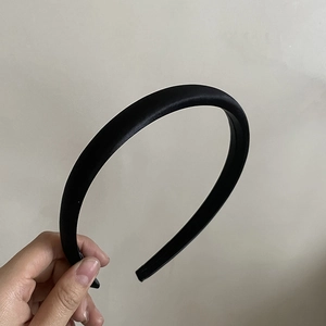 Détail d'un serre-tête en satin noir montrant la texture lisse et la largeur du bandeau