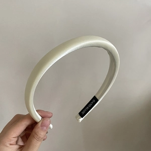 Détail d'un serre-tête en satin rembourré blanc crème avec étiquette fait main à l'intérieur