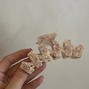 Dettaglio di un grande fermaglio per capelli in acetato con motivo marmorizzato beige