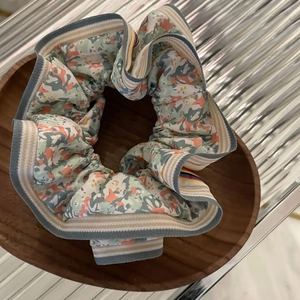 Chouchou floral oversize avec étiquette arc-en-ciel sur plateau en bois et métal