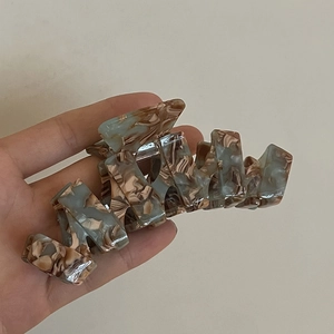 Dettaglio del grande fermaglio per capelli in acetato con motivo marmorizzato blu e marrone