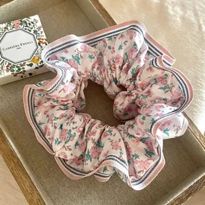 Détail d'un chouchou floral avec bordures rayées sur un plateau avec bougie parfumée