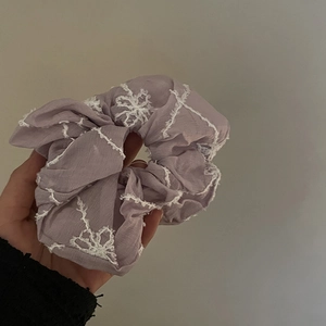 Gentle lavender scrunchie with white lace floral embroidery and ruffled chiffon texture