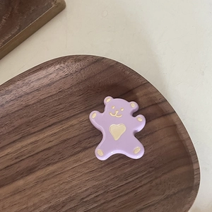 Vue macro détaillée d'une pince ours violette avec motif de cœur sur plateau en bois
