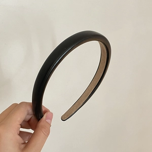 Close-up of black leather headband with brown non-slip lining shown in hand
