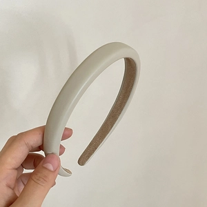 Close-up of padded cream faux leather headband with non-slip brown lining detail