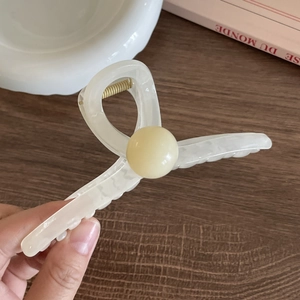 Close-up of cream marble acrylic hair claw clip with a pale yellow bead detail