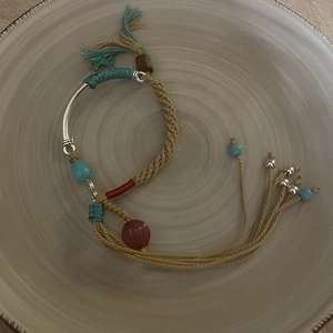 Ethnic style woven bracelet with silver metal tube and beads on ceramic plate