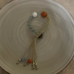 Detail of hand-woven bracelet with light blue beads and orange accent in ethnic style