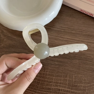 Cream white acrylic claw clip with matte green ball detail and gold metal spring