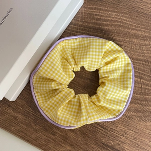 Floral plaid scrunchie with yellow gingham fabric and purple trim on wooden background