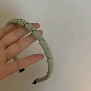 Detail of green woven fabric headband featuring a textured herringbone braided design