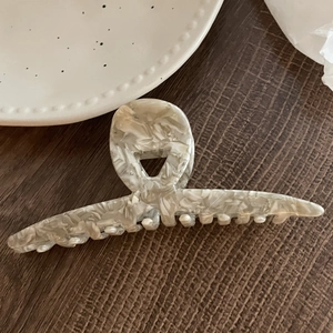 Vue détaillée d'une grande pince à cheveux en acétate marbré sur surface boisée