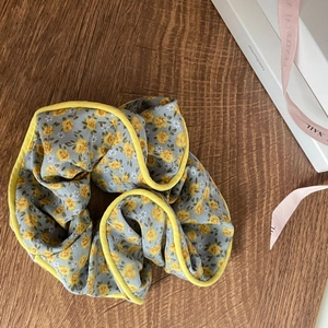 Close-up of light blue floral scrunchie with yellow trim on a wooden background