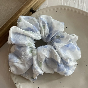 Vue détaillée du chouchou blanc fleuri aux bords effilochés sur assiette céramique