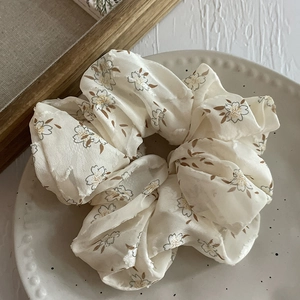 Détail d'un chouchou en mousseline fleurie avec fleurs à contour marron sur crème