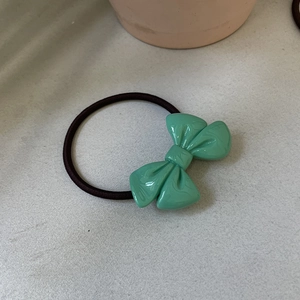 Detailed macro of mint green resin bow hair tie with smooth marbled texture finish