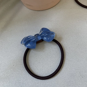 Close-up of translucent blue resin bow hair tie with a textured fabric effect finish