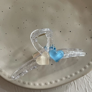Détail d'une pince à cheveux en résine transparente avec cœurs 3D sur plat en céramique