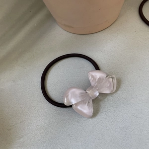Detail showing creamy pink resin bow on high-elasticity black rubber hair tie