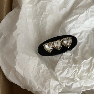 Detailed close-up of vintage black hair clip with three sparkling heart-shaped rhinestones