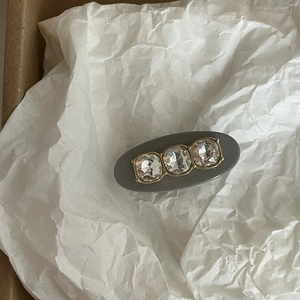 Elegant oval hair clip with three large rhinestones on dark grey matte base