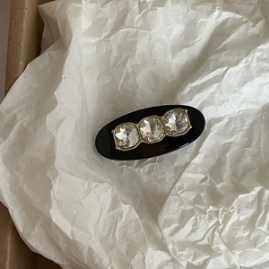 Elegant black oval hair clip featuring three sparkling rhinestones in gold claw settings